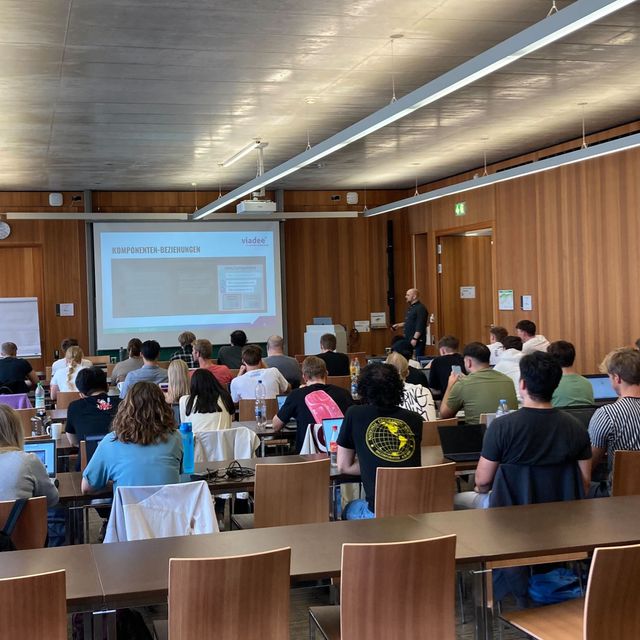 Bachelor-Studierende der Wirtschaftsinformatik an der Universität Köln sitzen im Hörsaal und hören den berater:innen der viadee zu.