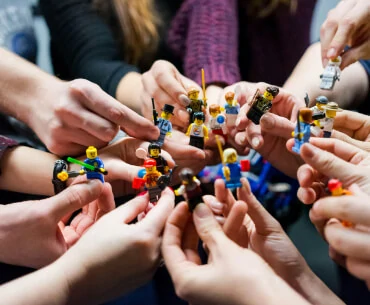 Mitarbeiter:innen der viadee halten Lego-Figuren in die Kamera.
