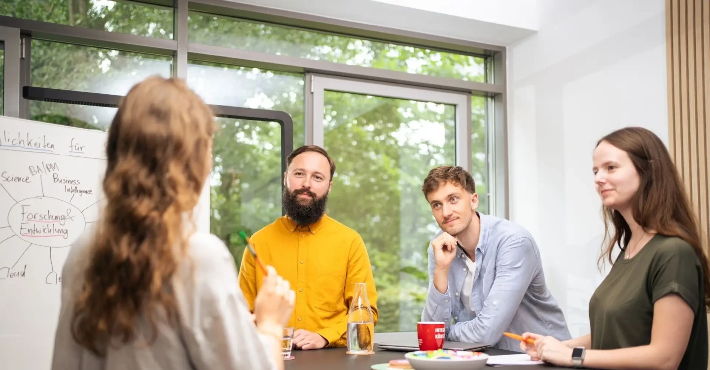 Drei Werkstudierende der viadee arbeiten mit einem Berater der viadee zusammen.