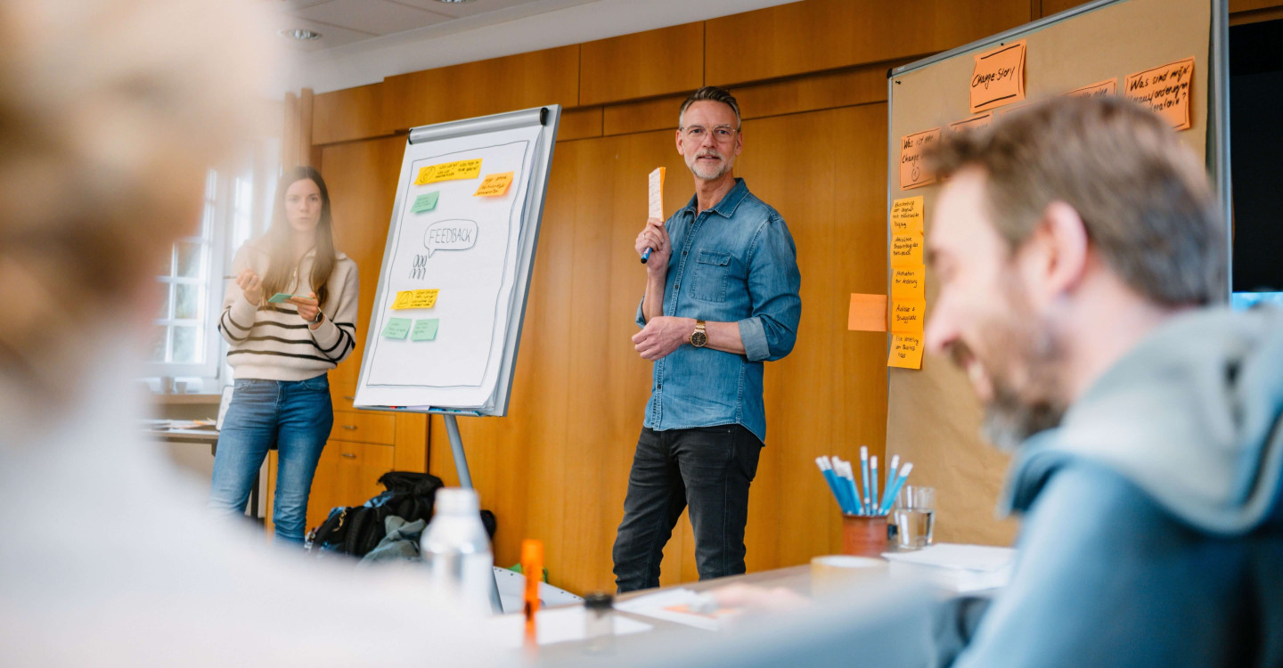 Zwei Mitarbeiter:innen der viadee stehen neben einem Flipboard und arbeiten mit ihrem Team zusammen.
