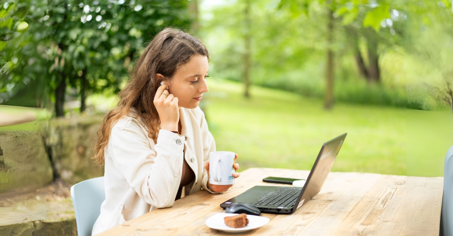 Eine Werkstudentin der viadee arbeitet im Homeoffice im Garten.