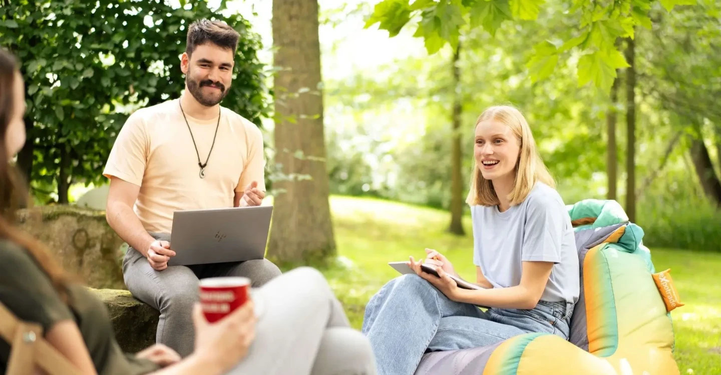 Drei Werkstudierende der viadee besprechen etwas. Sie sind im Garten.