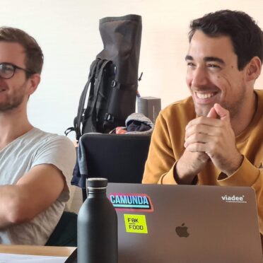 Zwei Seminar-Teilnehmer sitzen an einem Schreibtisch und lächeln freundlich.